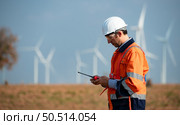 Engineer at Natural Energy Wind Turbine site with a mission to take care of large wind turbines Use a walkie talkie to communicate with a colleague working on top of the wind turbine. Стоковое фото, агентство Ingram Publishing / Фотобанк Лори