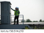 A team of electrical engineers is inspecting an energy storage station of a solar panels in the middle of a hundred acre field of solar panels. Стоковое фото, агентство Ingram Publishing / Фотобанк Лори