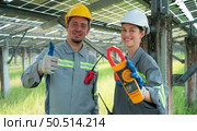 A team of electrical engineers is inspecting and maintaining solar panels at a solar panel site in the middle of a hundred acre field. Стоковое фото, агентство Ingram Publishing / Фотобанк Лори