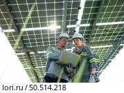 A team of electrical engineers is inspecting and maintaining solar panels at a solar panel site in the middle of a hundred acre field. Стоковое фото, агентство Ingram Publishing / Фотобанк Лори