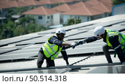 Both of Engineer in charge of solar panel installation The installation of solar energy conversion into electricity for a warehouse is currently being investigated. Стоковое фото, агентство Ingram Publishing / Фотобанк Лори