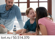 Father and mother with little boy have fun playing with your new toys in the bedroom together. Toys that enhance children’s thinking skills. Стоковое фото, агентство Ingram Publishing / Фотобанк Лори