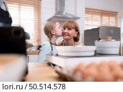 Grandparents with grandchildren and children gather in the kitchen to prepare the day’s dinner. Стоковое фото, агентство Ingram Publishing / Фотобанк Лори