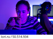 Asian women who rely heavily on computers to watch drama series until having to eat instant noodles in front of it, The game room has computers and LED neon lights that are spectacular. Стоковое фото, агентство Ingram Publishing / Фотобанк Лори