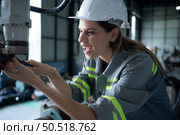 Female Technician Inspecting and repairing robotics arm in robots hangar and test the operation of the machine after being used for a while, as well as updating the software and calibration. Стоковое фото, агентство Ingram Publishing / Фотобанк Лори