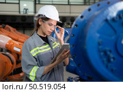 A female engineer installs a program on a robotics arm in a robot warehouse. And test the operation before sending the machine to the customer. Стоковое фото, агентство Ingram Publishing / Фотобанк Лори