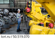 A female engineer installs a program on a robotics arm in a robot warehouse. And test the operation before sending the machine to the customer. Стоковое фото, агентство Ingram Publishing / Фотобанк Лори