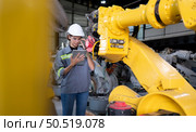 A female engineer installs a program on a robotics arm in a robot warehouse. And test the operation before sending the machine to the customer. Стоковое фото, агентство Ingram Publishing / Фотобанк Лори