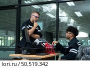 The robotic hand technology teacher is instructing new students on how to use electronic circuit boards and robotic hand commands for a variety of industrial applications. Стоковое фото, агентство Ingram Publishing / Фотобанк Лори