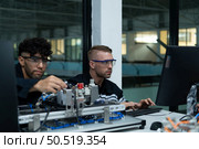 The robotic hand technology teacher is instructing new students on how to use electronic circuit boards and robotic hand commands for a variety of industrial applications. Стоковое фото, агентство Ingram Publishing / Фотобанк Лори