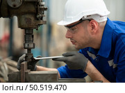 Young male engineers with experience are maintaining and testing the functionality of welding robots. After the hardwork of welding robots. Стоковое фото, агентство Ingram Publishing / Фотобанк Лори