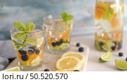 Summer healthy cocktails of citrus infused waters, lemonades or mojitos, with lime lemon orange blueberries and mint, diet detox beverages, in glasses on light background. Стоковое фото, агентство Ingram Publishing / Фотобанк Лори