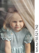 Curious Girl Gazing Through the Window, Embracing a World Full of Wonder and Imagination. Стоковое фото, фотограф Aleksandr Golubev / Фотобанк Лори