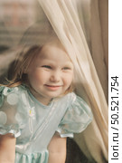 Curious Girl Peering Through a Window on a Sunny Afternoon. Стоковое фото, фотограф Aleksandr Golubev / Фотобанк Лори