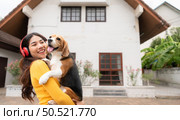 Young Asian woman holding up beagle dog after running around the house with the owner until exhausted and tired. Стоковое фото, агентство Ingram Publishing / Фотобанк Лори