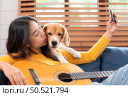 Beagle dog joining the owner’s selfie on the sofa in the living room of the house. Стоковое фото, агентство Ingram Publishing / Фотобанк Лори