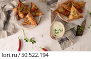 Indian samosas  - fried or baked pastry with savoury filling, popular Indian snacks, served in areca leaf dishes with spices on kitchen countertop. Стоковое фото, агентство Ingram Publishing / Фотобанк Лори