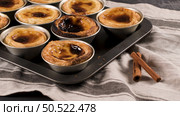 Rows of freshly cooked egg tarts, traditional portuguese dessert, pastel de nata, custard tarts on metal tray. Стоковое фото, агентство Ingram Publishing / Фотобанк Лори