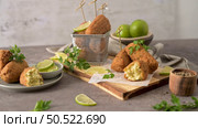 Cod dumplings, or "bolinhos de bacalhau" and parsley leaves and lemons on wooden cutting board in a kitchen counter top. Стоковое фото, агентство Ingram Publishing / Фотобанк Лори