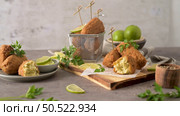 Cod dumplings, or "bolinhos de bacalhau" and parsley leaves and lemons on wooden cutting board in a kitchen counter top. Стоковое фото, агентство Ingram Publishing / Фотобанк Лори