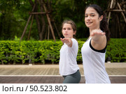 Young female and little girl disciple in the garden there are wooden walkways and a tunnel of fresh green trees. with yoga activities for health. Стоковое фото, агентство Ingram Publishing / Фотобанк Лори