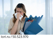 Woman sneezing in tissue due to allergy to pollen. Стоковое фото, агентство Ingram Publishing / Фотобанк Лори
