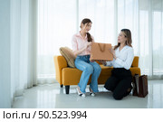 The receptionist delivers the goods that the customer has already purchased to Asian women on the sofa with shopping bags. Стоковое фото, агентство Ingram Publishing / Фотобанк Лори