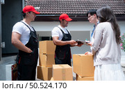 Delivery man handing over parcel boxes to customer in front of truck and the customer signs for the box in the document. Стоковое фото, агентство Ingram Publishing / Фотобанк Лори