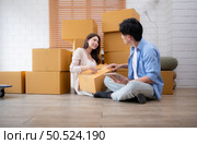 Young asian couple checking boxes being transported into new home with tablet. Стоковое фото, агентство Ingram Publishing / Фотобанк Лори