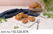 Meat patties and parsley leaves on white ceramic dishes in a kitchen counter top. Стоковое фото, агентство Ingram Publishing / Фотобанк Лори