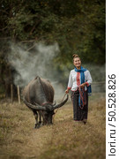 A woman walks holding a buffalo rope in the meadow. Стоковое фото, агентство Ingram Publishing / Фотобанк Лори