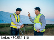 Young chief engineer is complain the trainee man on site of solar power plant, solar panel on background. Стоковое фото, агентство Ingram Publishing / Фотобанк Лори