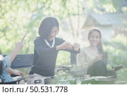 Young asian woman cooking and her friend enjoy to make the meal in pan, They are talk and laugh with fun together while camping in nature park. Стоковое фото, агентство Ingram Publishing / Фотобанк Лори