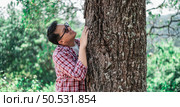 Portrait of Happy Asian man hugging a tree in forest. Protecting and love nature. Environment and ecology concept. Стоковое фото, агентство Ingram Publishing / Фотобанк Лори