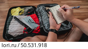 Close-up of man checks the checklist. He’s choosing clothes, travel documents, the itinerary for a solo trip. Travel, holiday and vacation concept. Стоковое фото, агентство Ingram Publishing / Фотобанк Лори