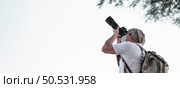 Asian traveler man with backpack taking a photo in the park with copy space. Travel photographer. Vocation and holiday concept. Стоковое фото, агентство Ingram Publishing / Фотобанк Лори