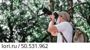Asian traveler man with backpack taking a photo in the park with copy space. Travel photographer. Vocation and holiday concept. Стоковое фото, агентство Ingram Publishing / Фотобанк Лори