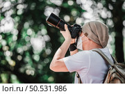 Asian traveler man with backpack taking a photo in the park with copy space. Travel photographer. Vocation and holiday concept. Стоковое фото, агентство Ingram Publishing / Фотобанк Лори