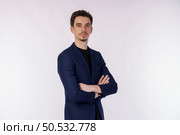 Portrait of young handsome businessman wearing suit standing with crossed arms with isolated on studio white background. Male smiling and looking at camera. Business and success concept. Стоковое фото, агентство Ingram Publishing / Фотобанк Лори