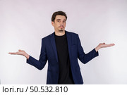 Portrait of puzzled clueless young businessman arms out asking why what’s the problem who cares so what, I don’t know on isolated background. Стоковое фото, агентство Ingram Publishing / Фотобанк Лори