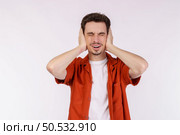 Portrait of attractive man close ears from noisy neighbours, looking up and shouting annoyed, hearing loud music on isolated background. . Стоковое фото, агентство Ingram Publishing / Фотобанк Лори