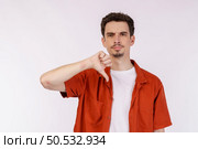 Portrait of young man shows sign of dislike, looks with negative expression and disapproval on isolated background. Disagreement, disgust and negative expressions. Стоковое фото, агентство Ingram Publishing / Фотобанк Лори