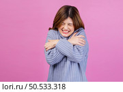 Portrait of Smiling young woman sweet winsome lovely attractive charming cheerful cheery lady hugging herself isolated over pink background. People lifestyle and expression concept. Стоковое фото, агентство Ingram Publishing / Фотобанк Лори
