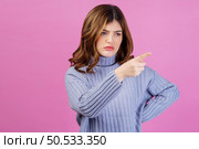 Portrait of angry sad young woman point index finger aside isolated over pink background. People lifestyle and emotion concept. Стоковое фото, агентство Ingram Publishing / Фотобанк Лори