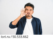 Portrait of Young asian man in blue shirt keeping a secret isolated on white background. Expression and lifestyle concept. Стоковое фото, агентство Ingram Publishing / Фотобанк Лори