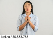 Portrait of Young asian woman in blue shirt looking at camera and exciting isolated on white background. Expression and lifestyle concept. Стоковое фото, агентство Ingram Publishing / Фотобанк Лори