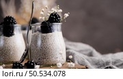Chia pudding with blackberries, three portions in glass jars on a dark table. Стоковое фото, агентство Ingram Publishing / Фотобанк Лори