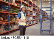Male clerk using digital tablet while standing on stairs in warehouse to inspect goods. Стоковое фото, агентство Ingram Publishing / Фотобанк Лори