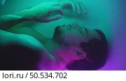 Human cloning - man lies in neon water as an embryo. Стоковое видео, видеограф Илья Шаматура / Фотобанк Лори