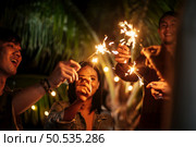 Portrait of Happy Asian group of friends having fun with sparklers outdoor - Young people having fun with fireworks at night time  - People, food, drink lifestyle, new year celebration concept. Стоковое фото, агентство Ingram Publishing / Фотобанк Лори